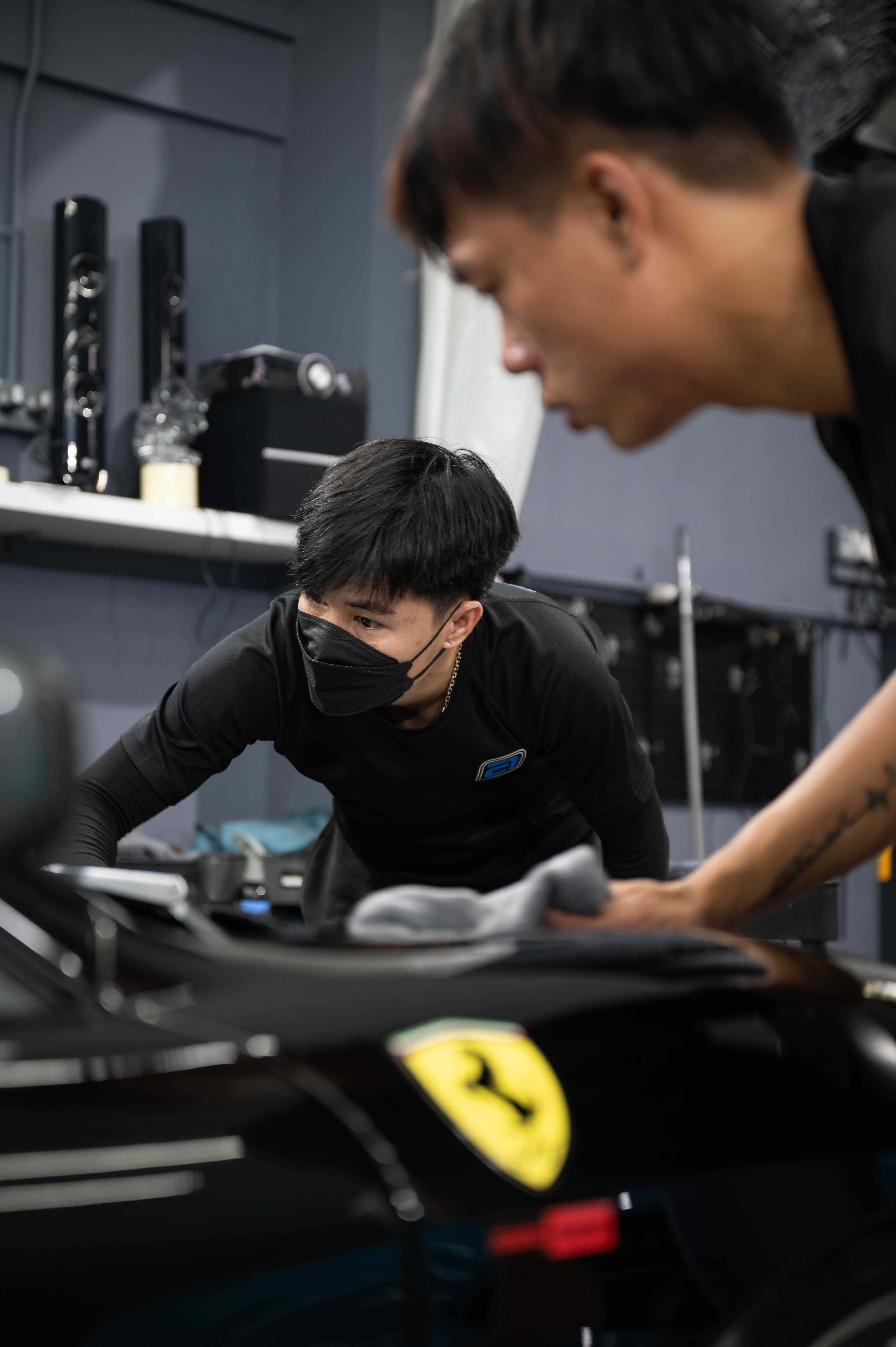 Detailer machine-polishing the rear quarter of a black Porsche